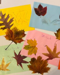Bunte Kinderbastelbilder mit echten Herbstblättern und Zeichnungen auf farbigem Papier aus der Großtagespflege Rappelkiste Hochdahl.